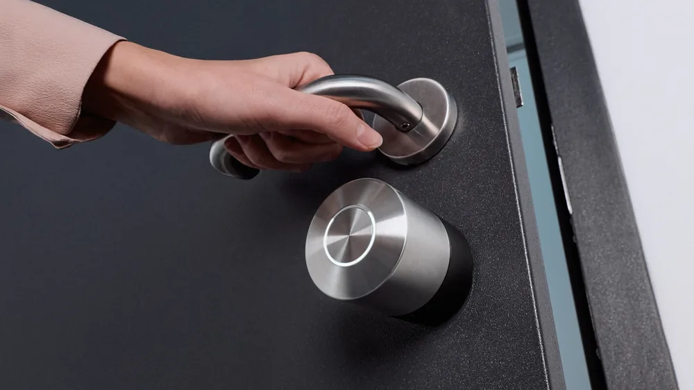 Mano sulla maniglia di una porta scura con Smart Lock Pro montata all'interno