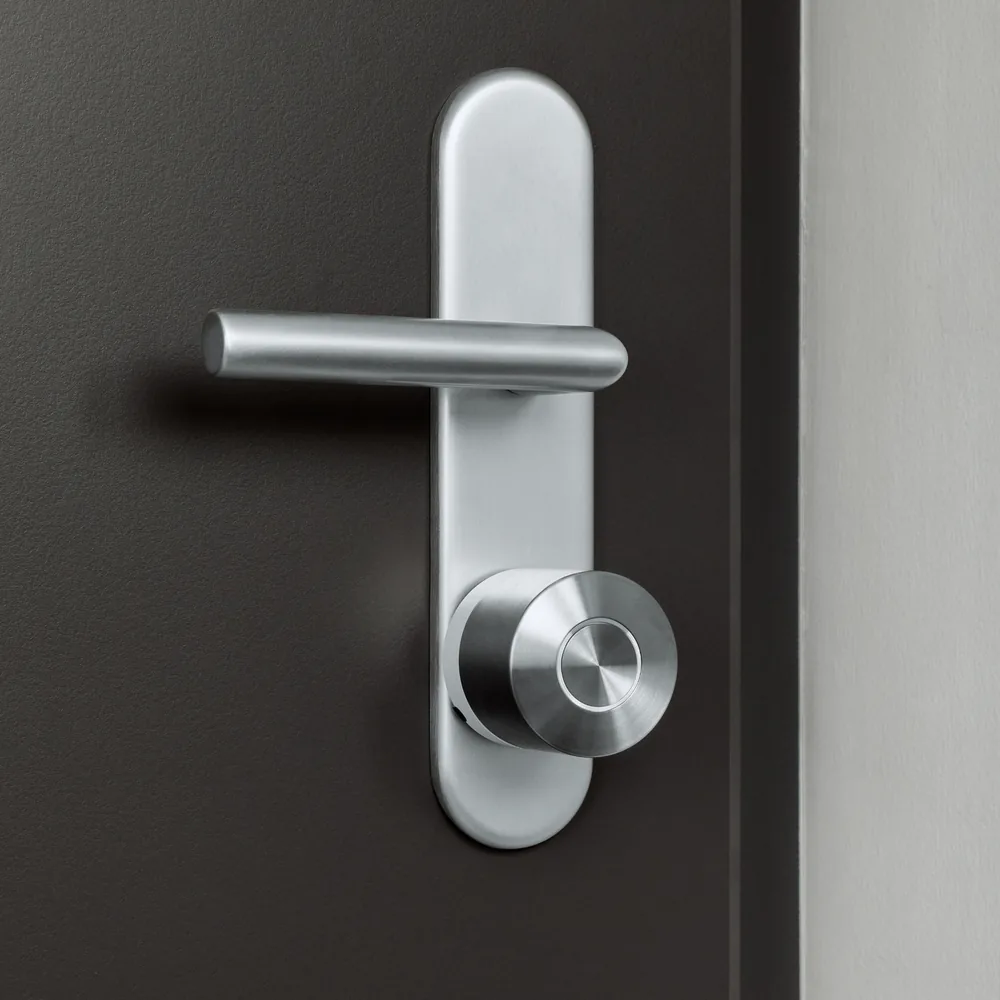 Nuki Smart Lock Ultra montata sotto la maniglia di una porta scura